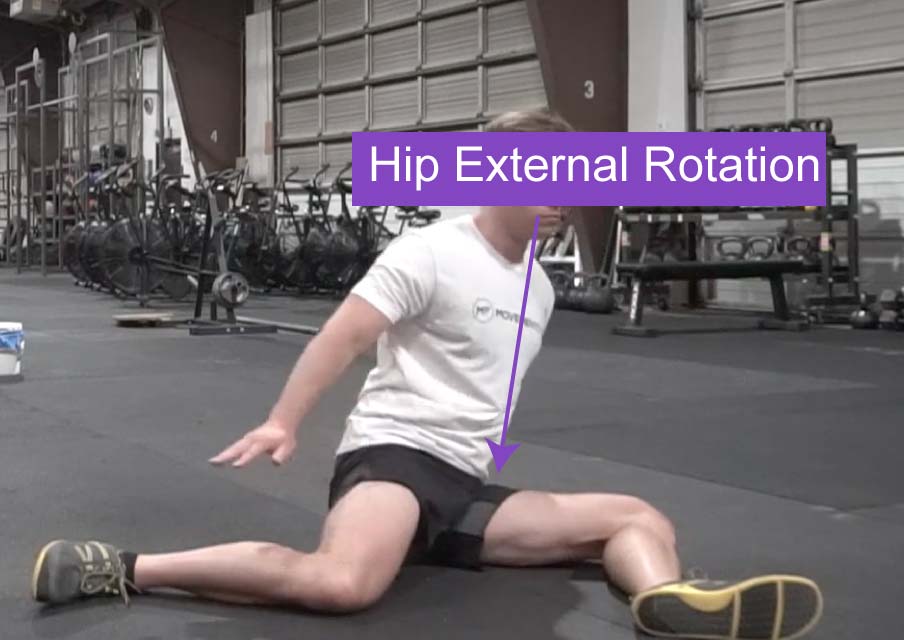 A man seated on the ground demonstrating hip joint external rotation